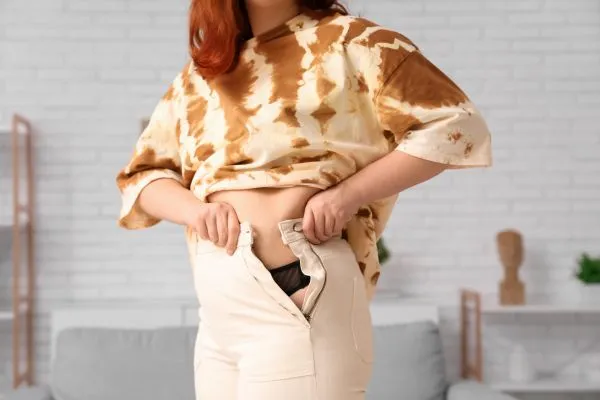 Image of woman trying to do her trousers up after pregnancy weight gain yorkshire