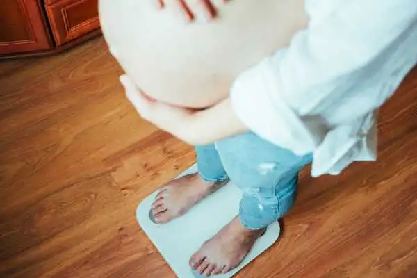 Image of woman weighing herself and experiencing weight gain through pregnancy yorkshire
